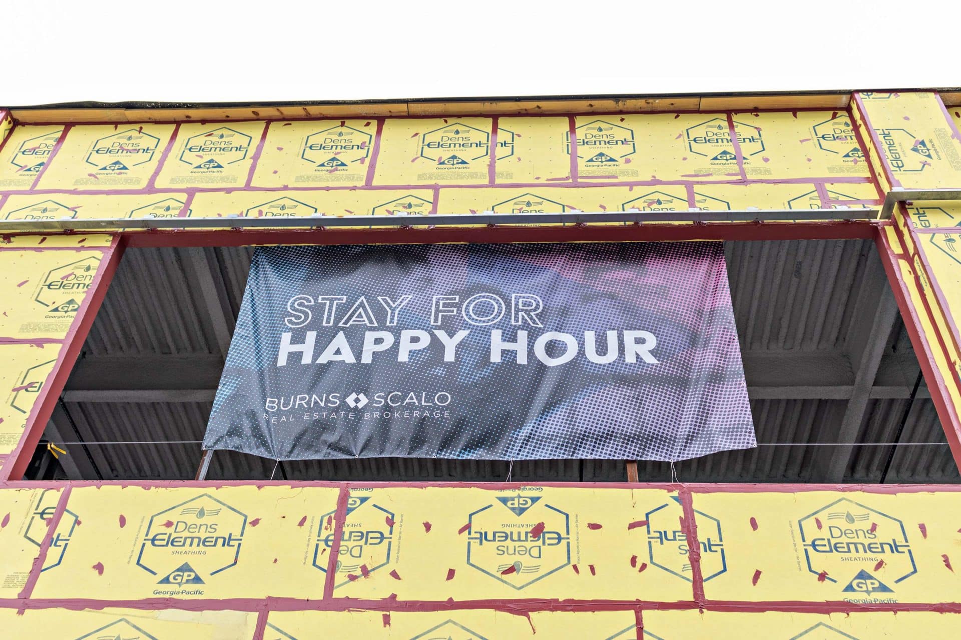 banner that reads stay for happy hour on side of building