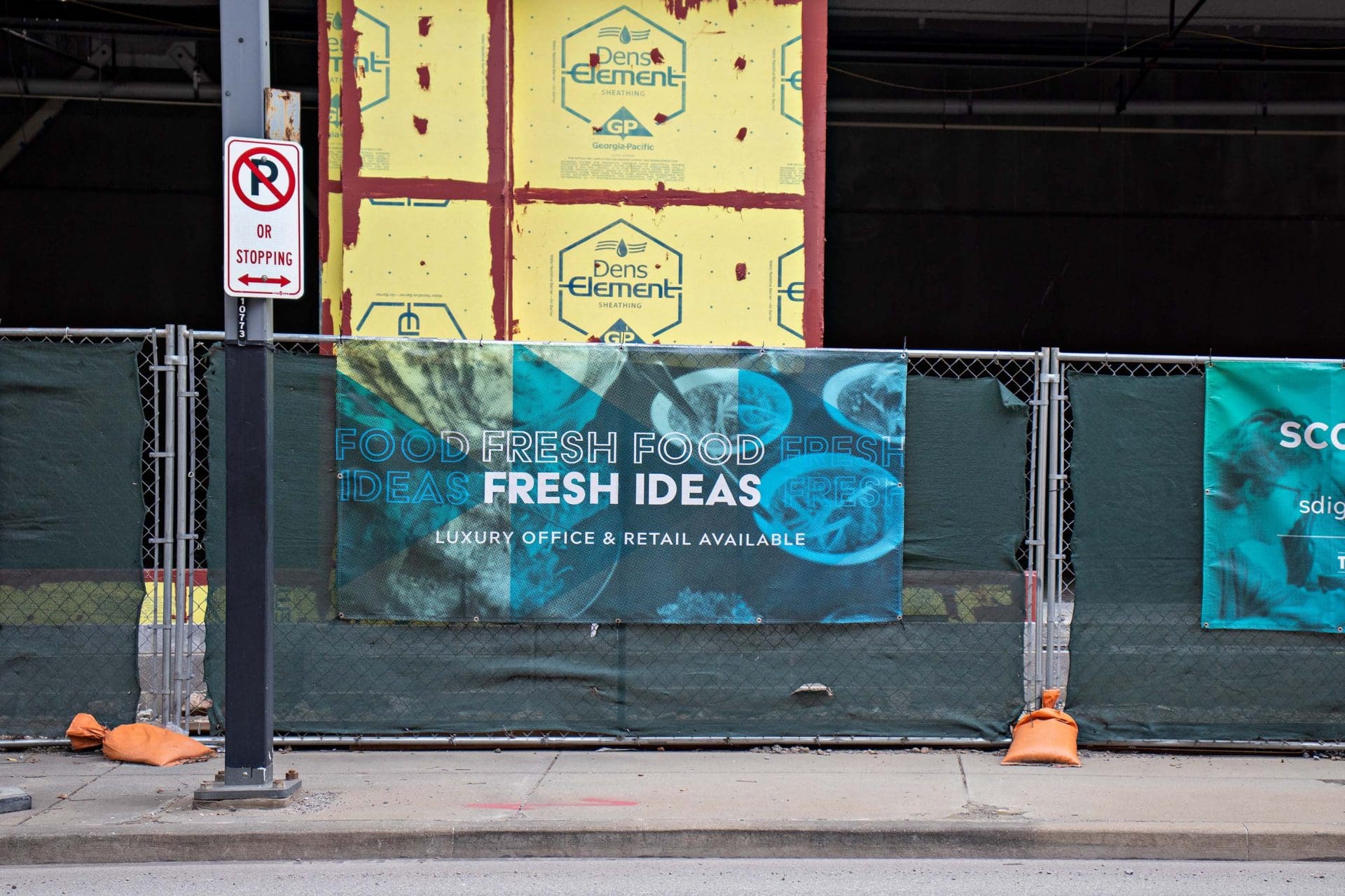 banner that reads fresh food fresh ideas on fence in front of building under construction