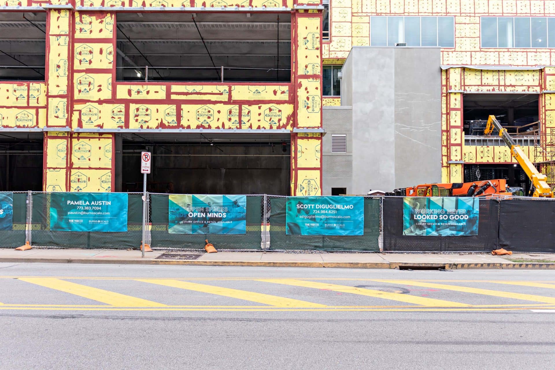 banners on fence in front of a building under construction